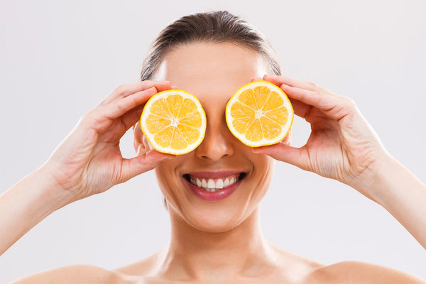 woman holding lemon halves over her eyes