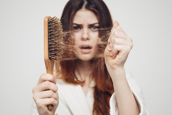 woman removing hair from her brush looking shocked