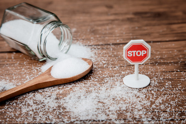 sugar on a wood spoon with a stop sign next to it 