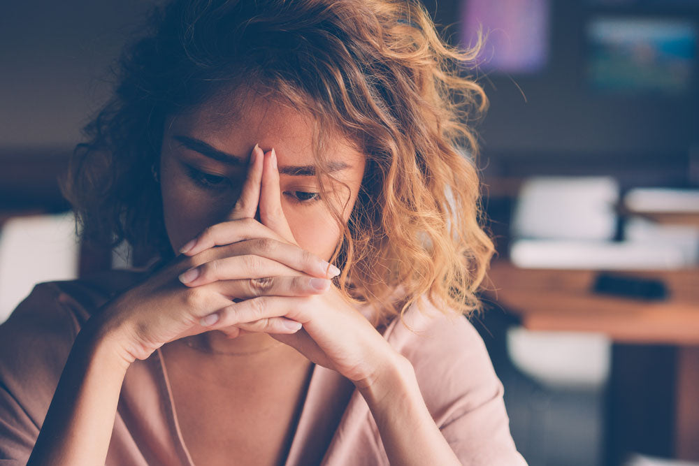 woman with her hands on her face looking stressed and defeated