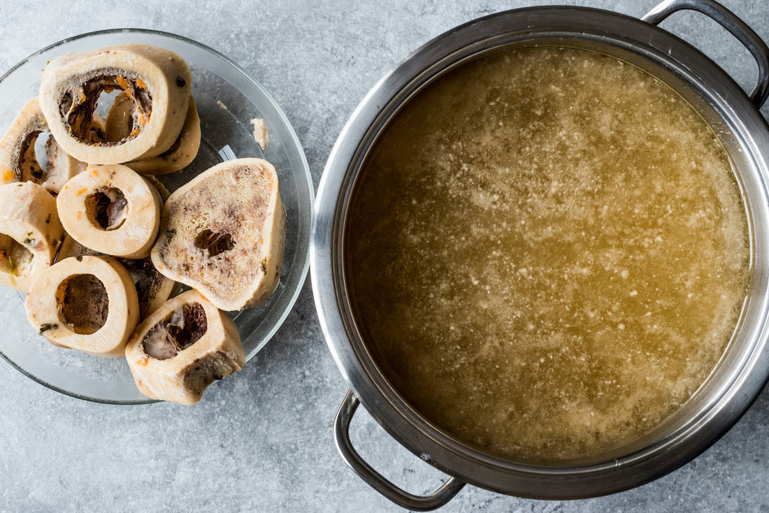 A pot of broth next to a bowl of bones
