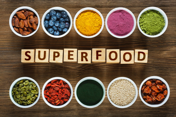The best anti-aging foods for women in containers surrounding the word "superfood".