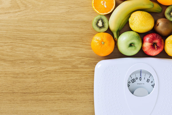 healthy fruits and a scale on a wood background