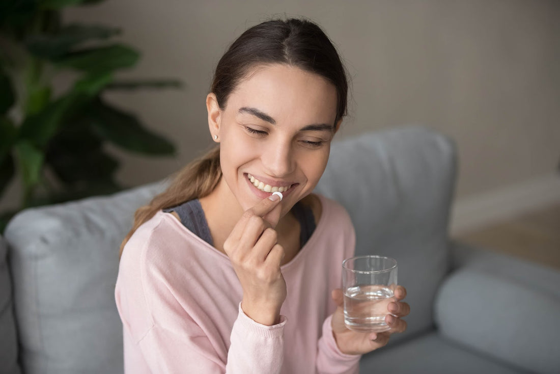 Woman taking a pill with a glass of water